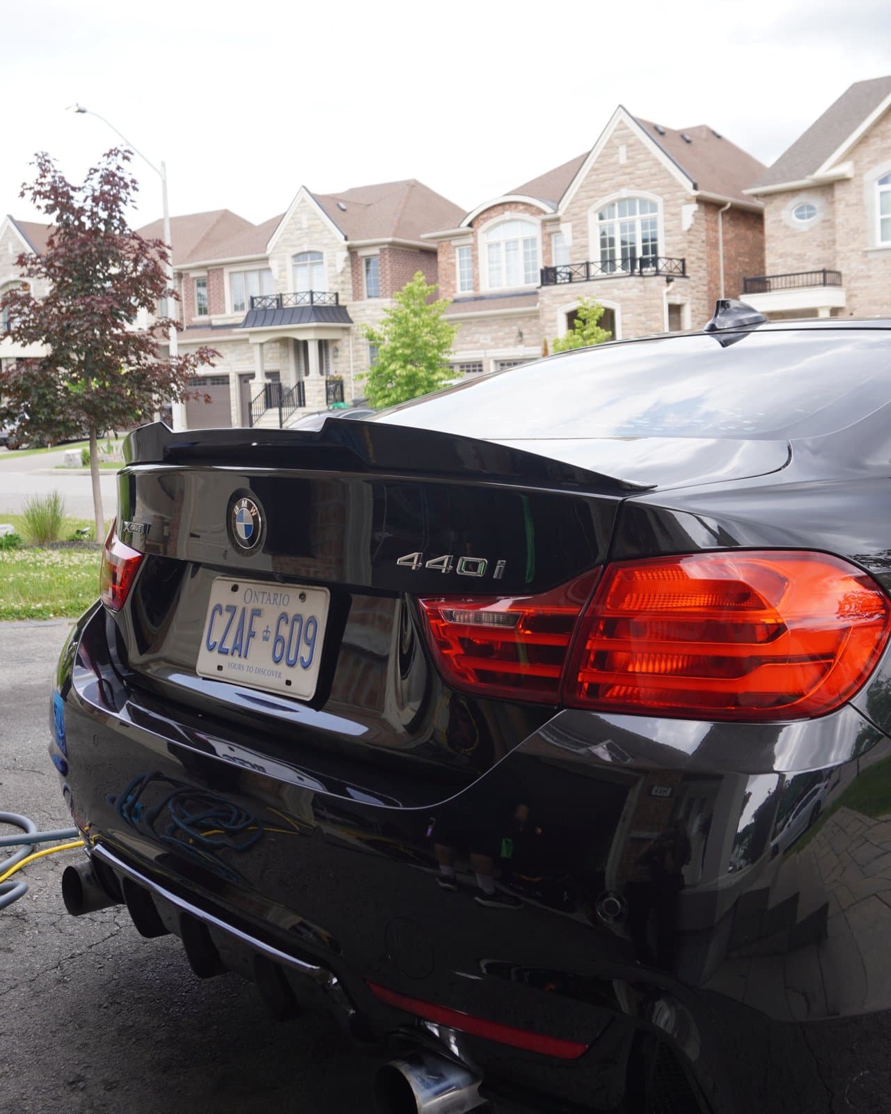 Rear three-quarter view of a detailed black BMW 440i in a driveway